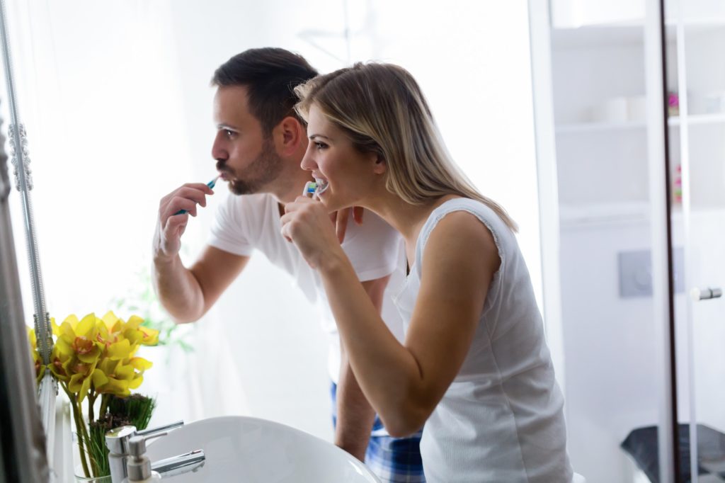 Attractive couple brushing teeth in morning together